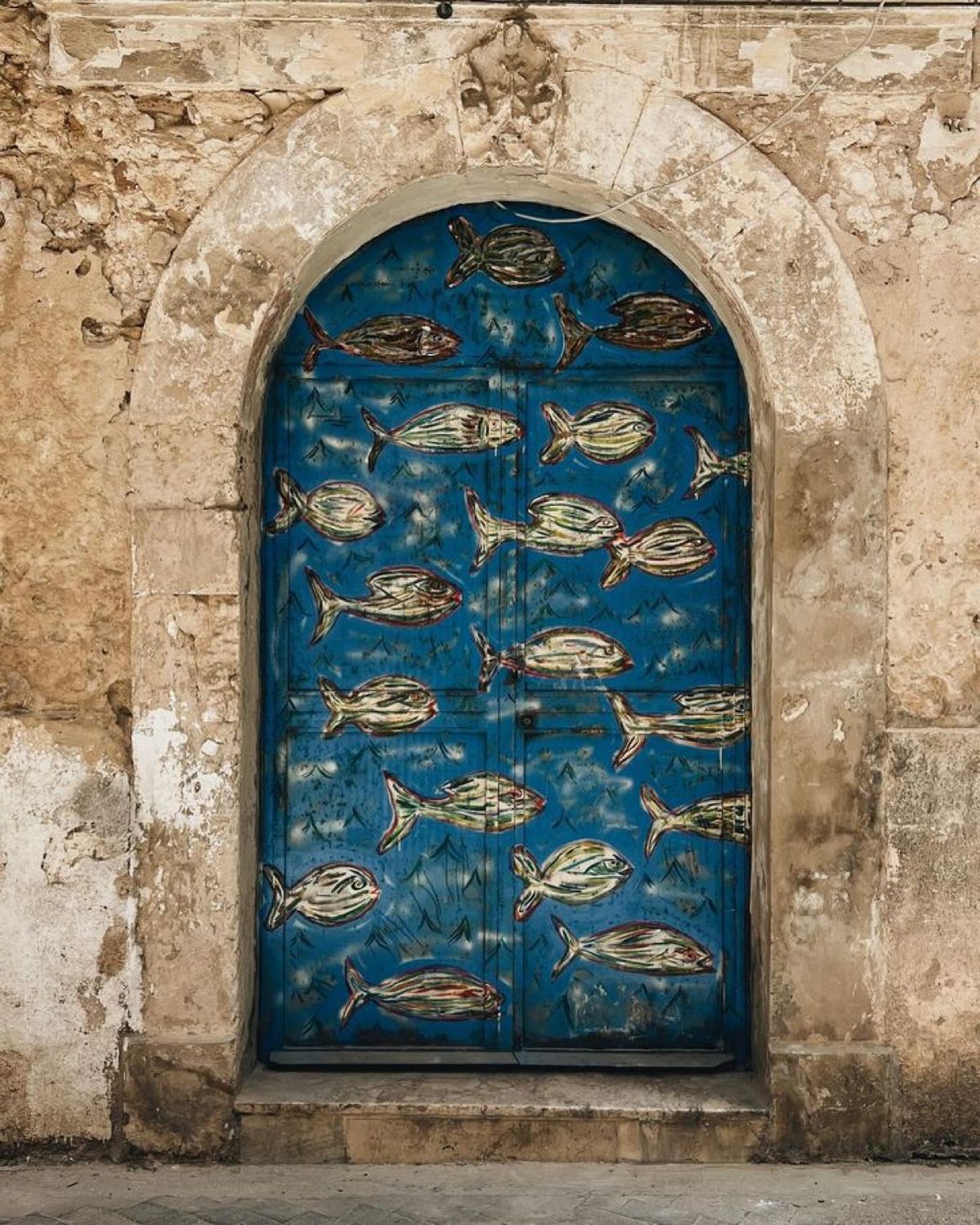 Porta blu con pesci dipinti — atmosfera mediterranea